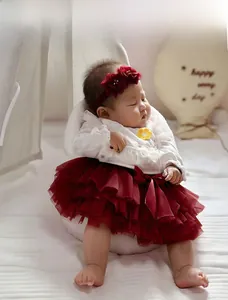 Detail of baby girl outfit showing yellow flower embroidery and wine red tutu skirt