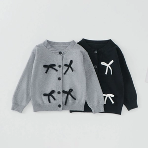 Détail de cardigans en tricot pour filles avec nœuds contrastés et bords-côtes