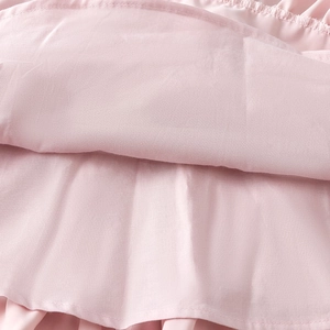 Macro detail of soft pink chiffon fabric layers and fine stitching on tiered dress