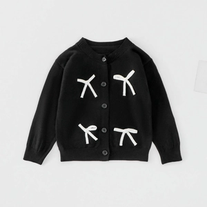 Détail du cardigan noir en maille avec nœuds blancs élégants et poignets côtelés fins