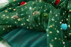 Detail of dark green tutu dress with golden stars and colorful 3D pom-pom decorations