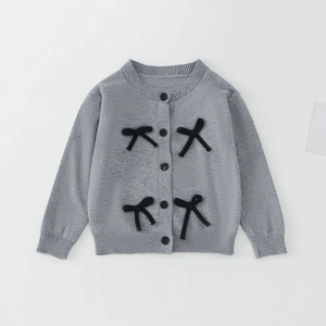 Détail d'un gilet gris tricoté pour fille avec nœuds 3D noirs et boutons ronds