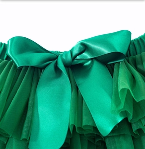 Detail of emerald green baby tutu skirt with large satin bow and layered mesh texture