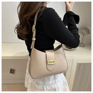 Detailed close-up of a beige faux leather baguette bag with a gold metal buckle fastener