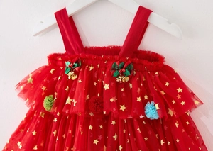 Detail of Christmas tutu dress featuring gold stars, festive bows, and plush pompoms