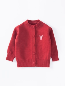 Détail d'un cardigan rouge pour fille avec broderie nœud et finitions côtelées