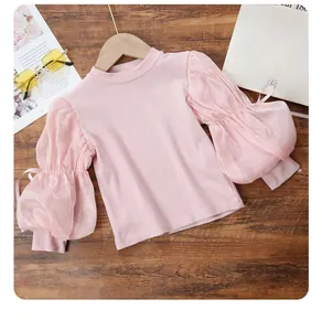 Pink rib-knit top with organza puff sleeves and bow detail on wooden background