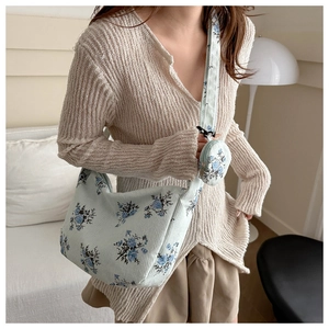 Close-up of light green corduroy hobo bag with blue floral patterns and a matching pouch