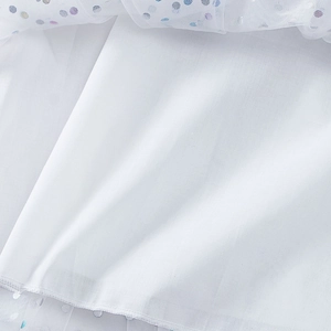 Détail du tulle blanc avec sequins colorés sur une robe de fête à bretelles pour fille