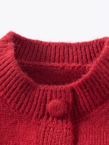 Gros plan du col côtelé du cardigan en tricot rouge et bouton recouvert de tissu assorti