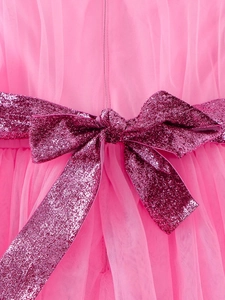 Pink tulle flower girl dress featuring a deep purple sequin bow at the waistline