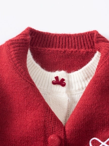 Gros plan du cardigan en tricot rouge avec nœud brodé et col côtelé doux pour fille