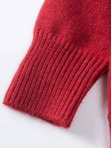 Gros plan des poignets en tricot côtelé de ce pull rouge pour fille au tissu doux