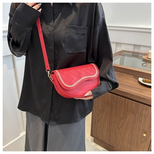 Detalle de bolso silla rojo con acolchado de rombos y cadena dorada sobre camisa negra
