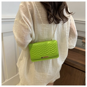 Detail of green quilted crossbody bag with golden chain strap and metallic lock clasp