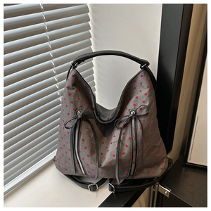 Detail of grey textured hobo bag with red heart prints and decorative black ribbons