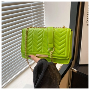 Detail of neon green crossbody bag with V-shaped quilting and gold chain strap