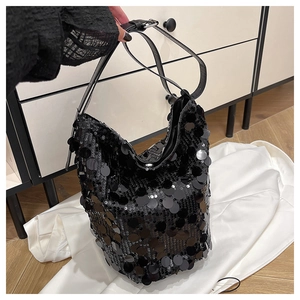 Dettaglio di una borsa a secchiello nera con paillettes riflettenti e tracolla in pelle