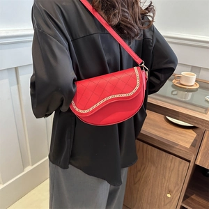 Sacoche selle rouge matelassée avec chaîne dorée portée à l'épaule par un mannequin
