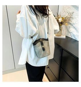 Detail of color-block bucket bag with golden twist lock and matte grey-green texture
