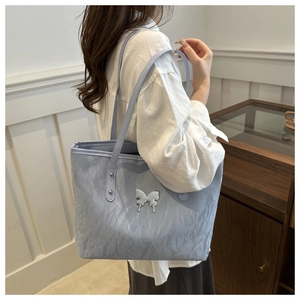 Detail of light blue waterproof tote bag with textured fabric and silver butterfly charm