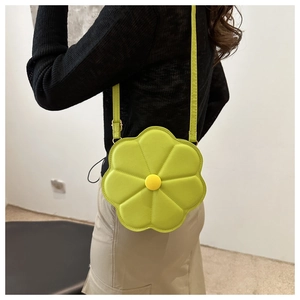 Dettaglio della borsa a tracolla verde a forma di fiore con centro giallo e texture in pelle PU
