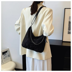 Détail d'un sac hobo croissant noir avec chaîne argentée et bandoulière en cuir lisse