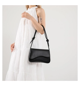 Close-up of the stylish knotted shoulder strap detail on this black leather handbag