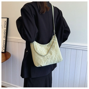 Détail du sac plissé jaune clair avec chaîne argentée et texture satinée lisse