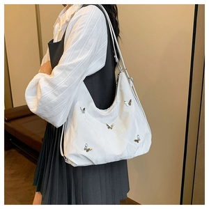 Detail of white pleated shoulder bag with silver butterfly charms on a model