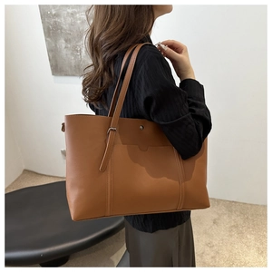 Caramel leather tote bag side view on shoulder showing large capacity and metal snap button