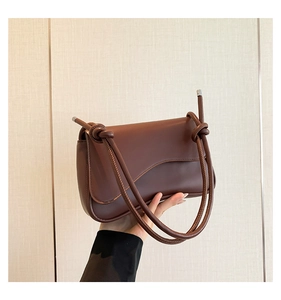 Détail d'un sac à bandoulière marron foncé avec sangle nouée et finitions argentées