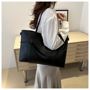 Minimalist black faux leather tote bag with stylish buckle strap shown on a model