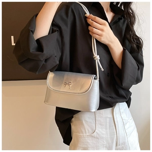 Silver metallic crossbody bag with delicate bow detail and satin finish on model