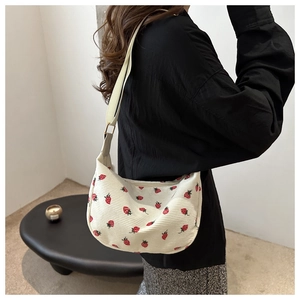 Detailed close-up of a white corduroy crescent bag with vibrant red strawberry prints