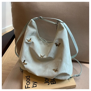 Detail of light green pleated hobo bag with gold butterfly buckles on a book