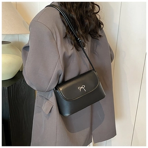 Detailed view of black matte leather shoulder bag with elegant silver bow metal buckle