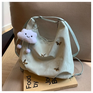 Detail of mint green nylon shoulder bag with golden butterfly buckles and plush cloud charm