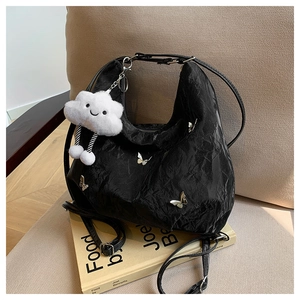 Detail of black pleated hobo bag with silver butterfly charms and plush cloud pendant