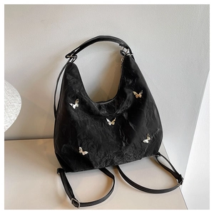 Detail showing black backpack with metallic butterfly charms and pleated nylon texture