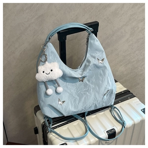 Close-up of light blue pleated bag with silver butterfly charms and white cloud pendant