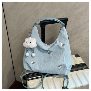 Detail of light blue textured hobo bag featuring metal butterflies and a cloud pendant