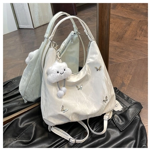 Close-up of white pleated bag with silver butterfly charms and fluffy cloud pendant