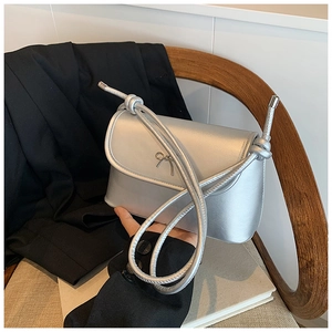 Silver faux leather crossbody bag with metallic finish and decorative bow detail