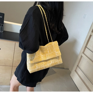 Detail of yellow and white jacquard tote bag with golden metal chain strap on model