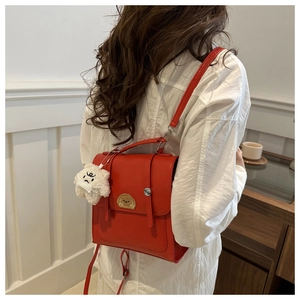 Detail of red PU leather backpack with cartoon dog badge and plush pendant on model