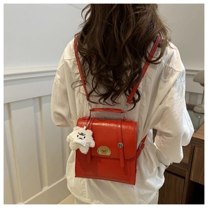 Red vintage backpack for women with gold animal clasp and white plush charm on back