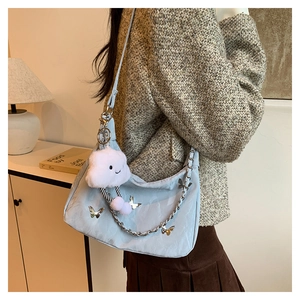 Detail of light blue hobo bag with silver butterfly metal charms and plush cloud pendant