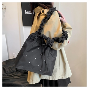 Detail of black drawstring bucket bag with white rhinestones and pleated shoulder strap