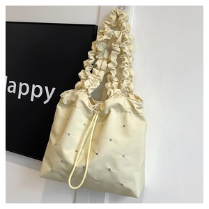 Detail of cream pleated tote bag with drawstring closure and sparkling rhinestones